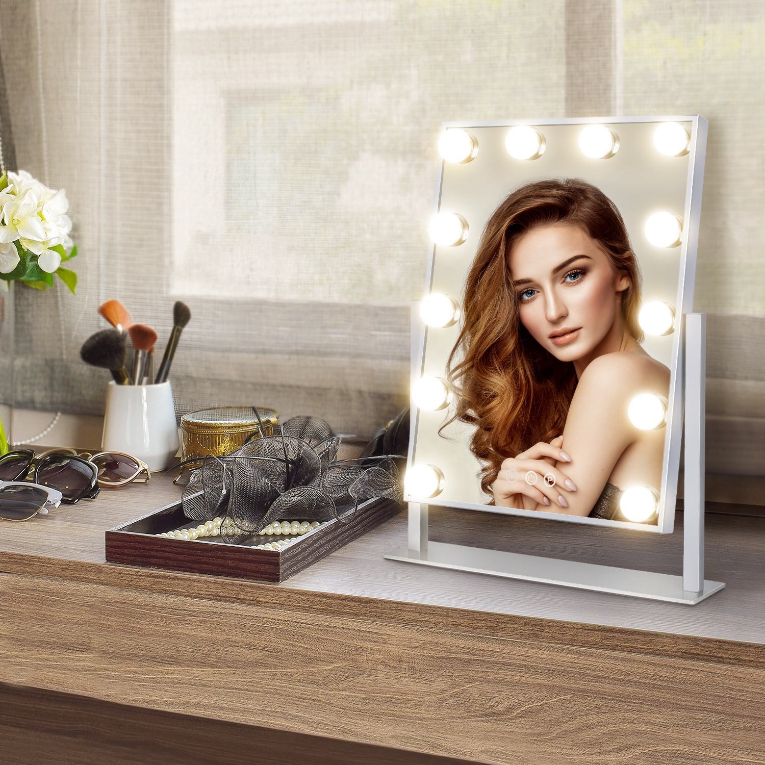 A woman with wavy hair applying makeup using a 12-bulb Hollywood-style LED mirror on a modern vanity table, showcasing the even and shadow-free illumination